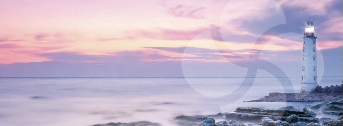 A seascape at sunset with a lighthouse on rocks on the right.